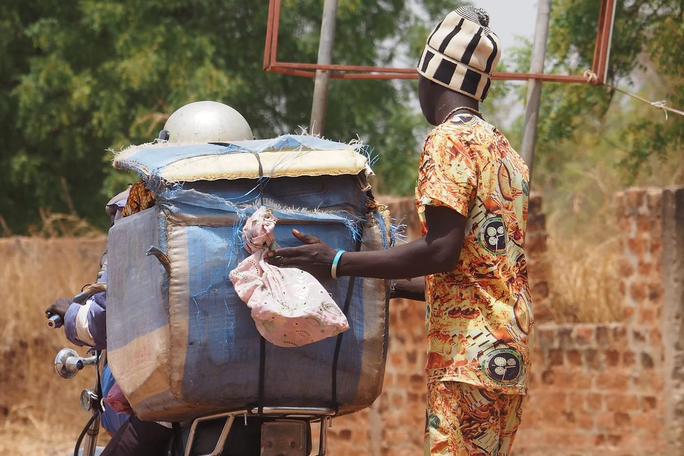 Mies ja tavaroilla lastattu moottoripyörä Gambian maaseudulla