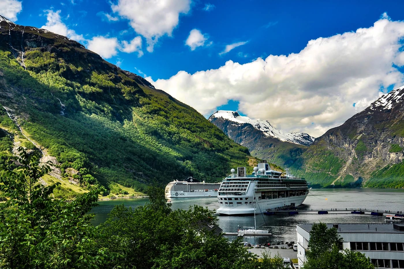 Risteilyalus Geirangervuonossa kylän ja vesiputouksen äärellä
