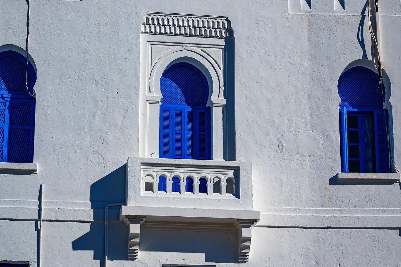 Valkoinen rakennus sinisine kaari-ikkunoineen Tunisiassa