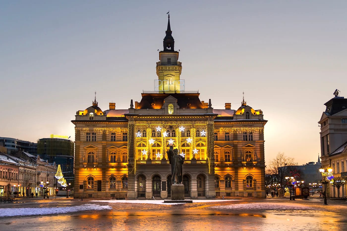 Novi Sadin raatihuone valaistuna auringonlaskussa