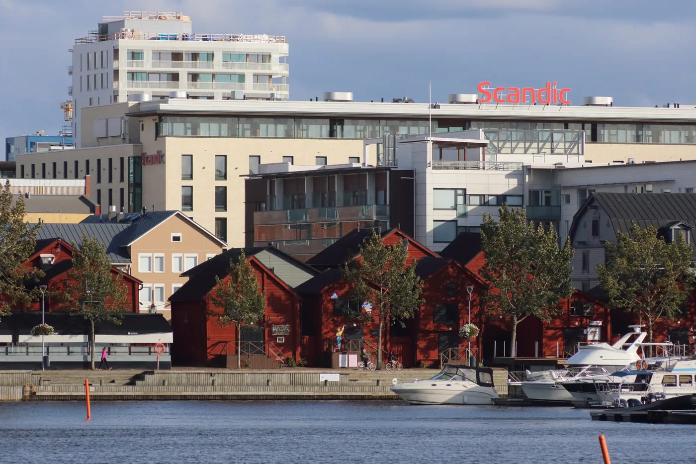 Punaiset makasiinirakennukset ja veneitä joen rannassa