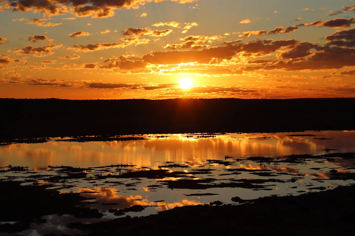 Auringonlasku heijastuu autiomaan vesialtaaseen