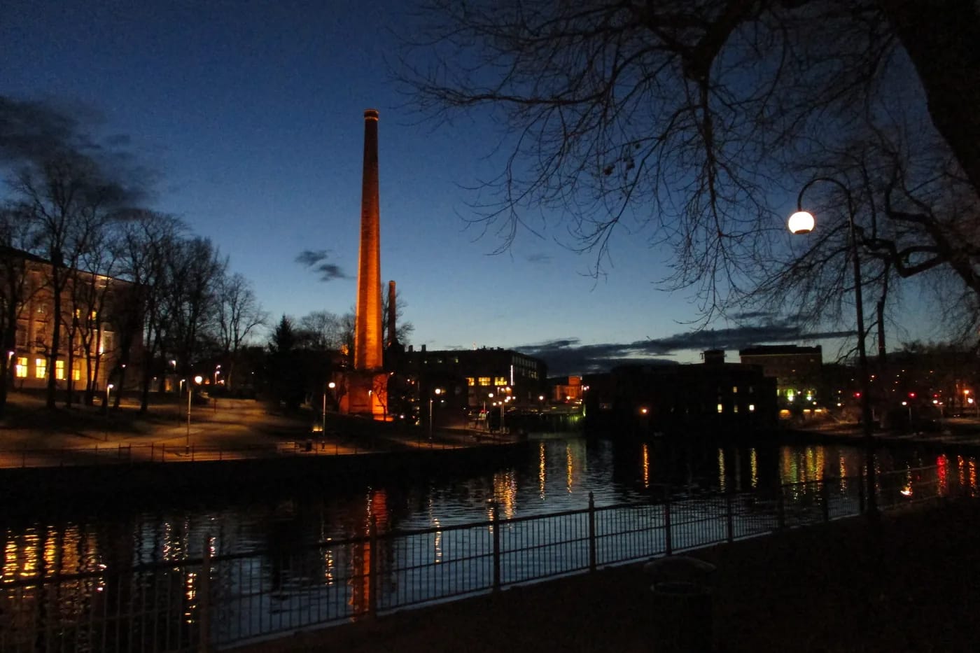 Tammerkoski ja valaistu tehtaanpiippu sinisellä hetkellä